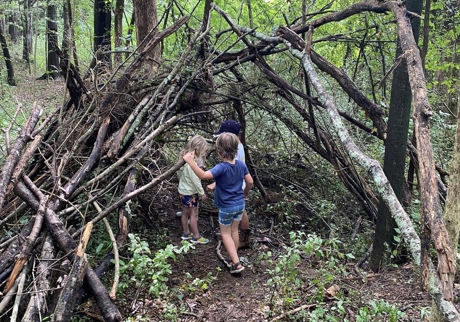 children in a stick fort in the woods