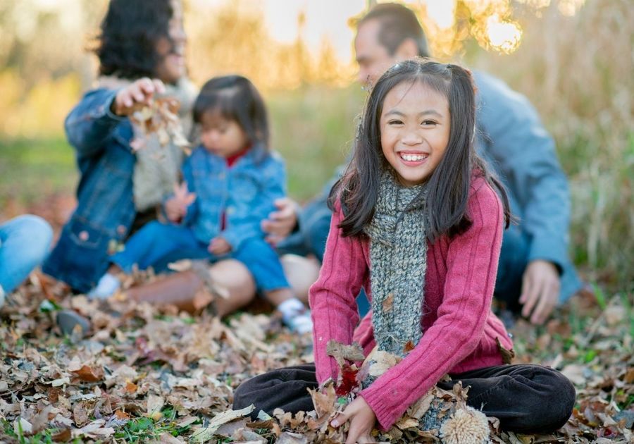 Girl playing in leaves with family