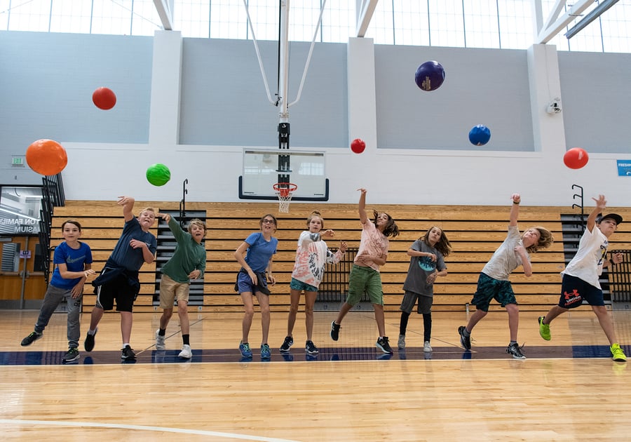 children throwing balls inside the gymnasium at Denver Academy Summer Camp
