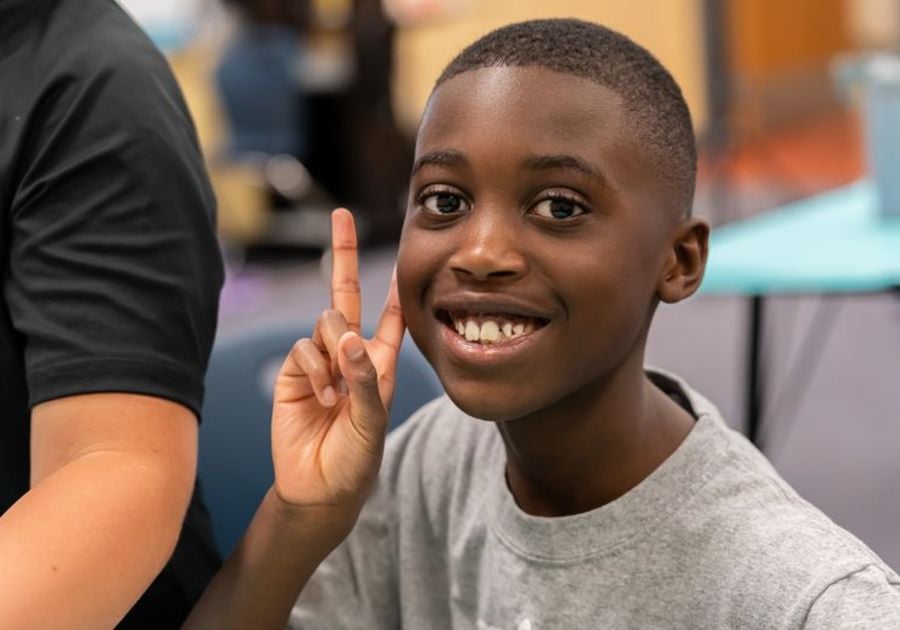 Boy holding up two fingers and smiling