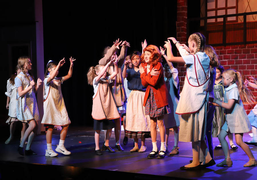 ensemble of girls performing Annie onstage