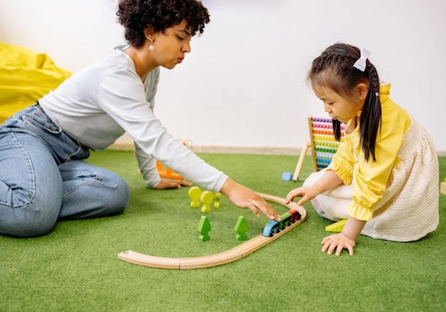 woman playing with a train set with a little girl