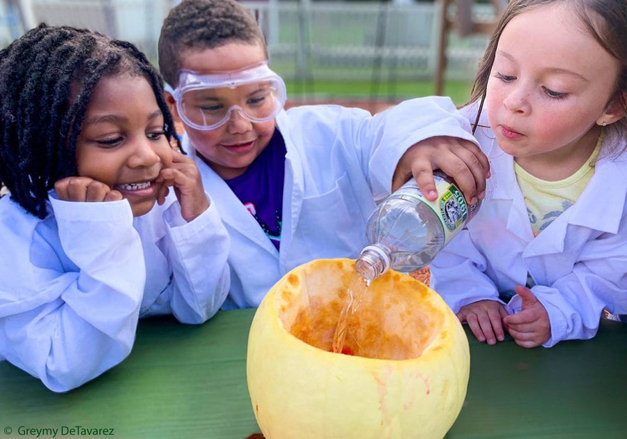 young children in white lab coats doing an experiment