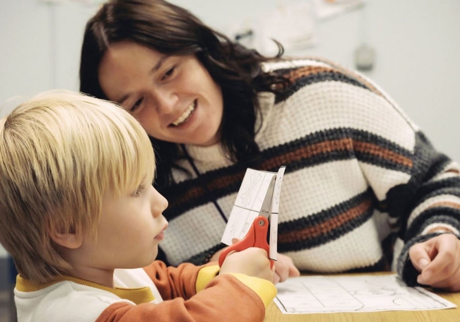 teacher helping student cut paper