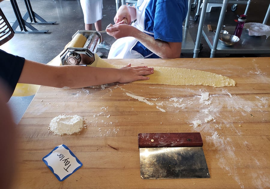 child rolling pasta in a cooking class