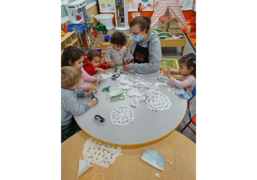 kids making paper snowflakes with teacher
