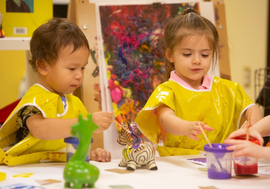 two little kids with yellow smocks painting