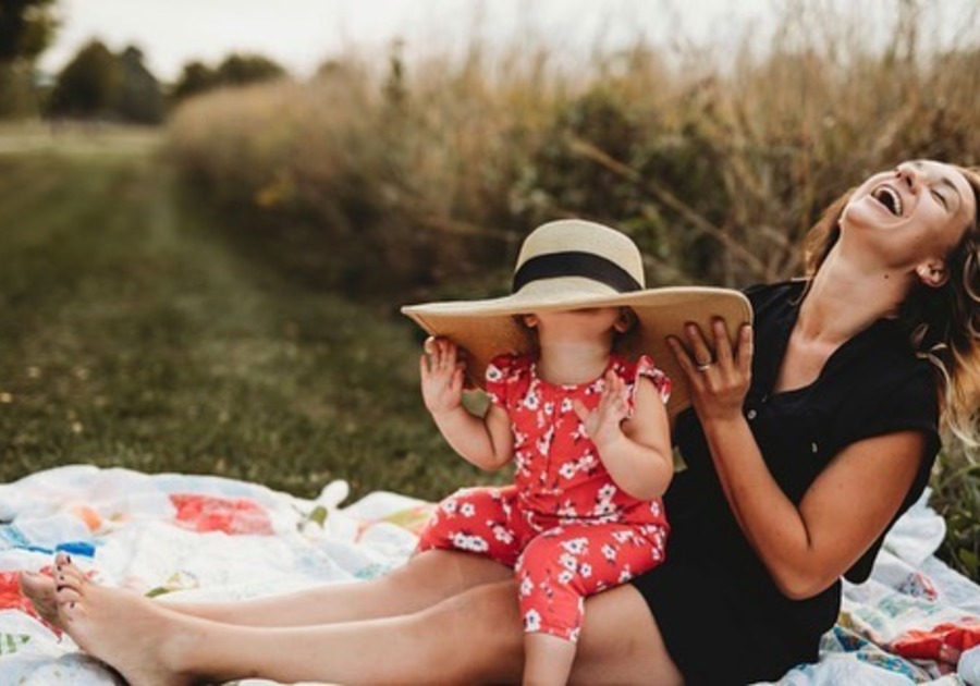 publisher and daughter laughing with oversized hat on daughter