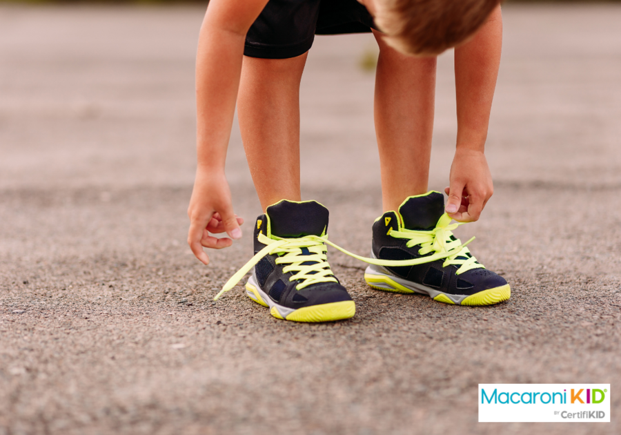 child tying shoelaces on sports shoes in summer