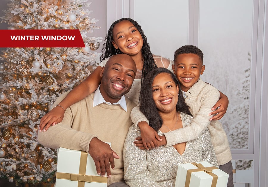 Family with young children smiling in cozy winter-themed portrait at JCPenney Portraits