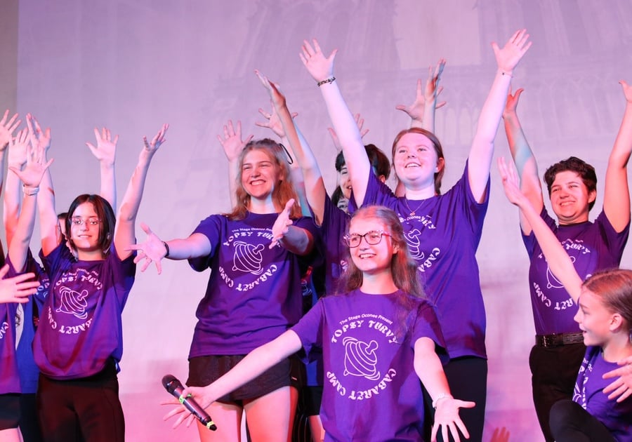 campers in purple shirts posing on stage