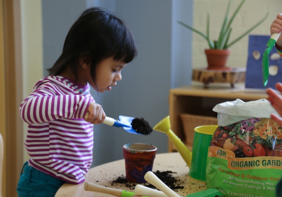 little girl putting soil in a pot