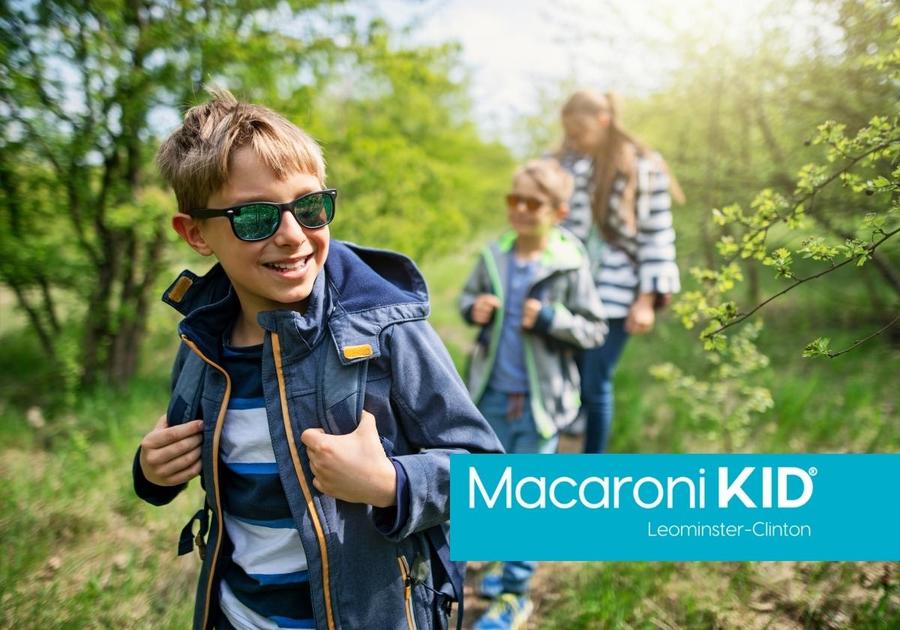 Three children walking through the woods with backpacks and sunglasses.