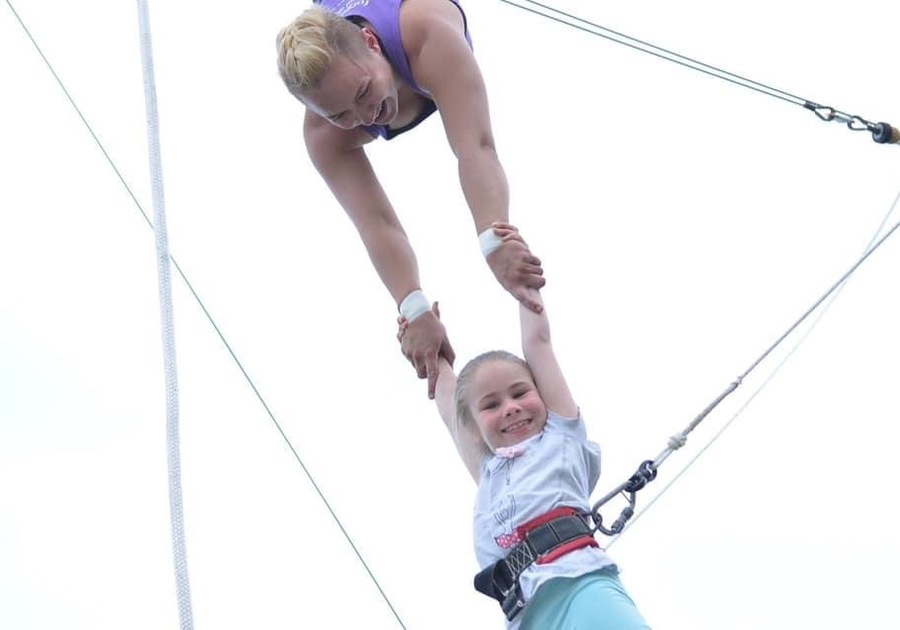 little girl being held by someone on trapeze