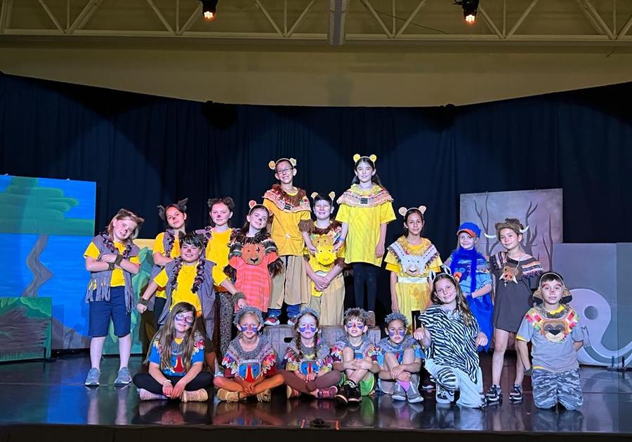 Costumed children sitting and standing on a stage in rows