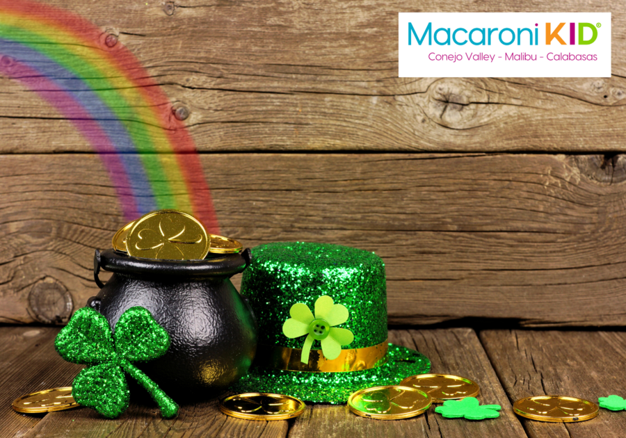 St. Patrick's Day, rainbow leading to a pot of gold coins, green glittery top hat and shamrock against a wood background