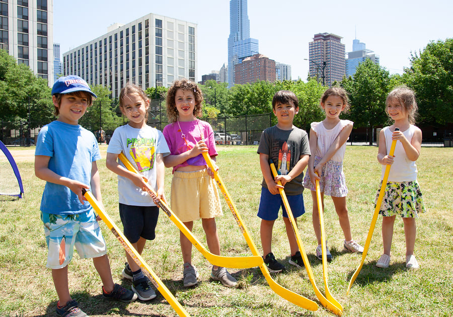 six kids holding yellow hockey sticks