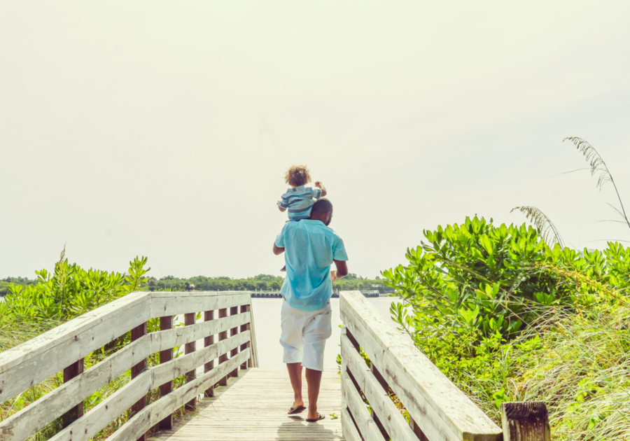 Father carrying child on shoulder on a bridge