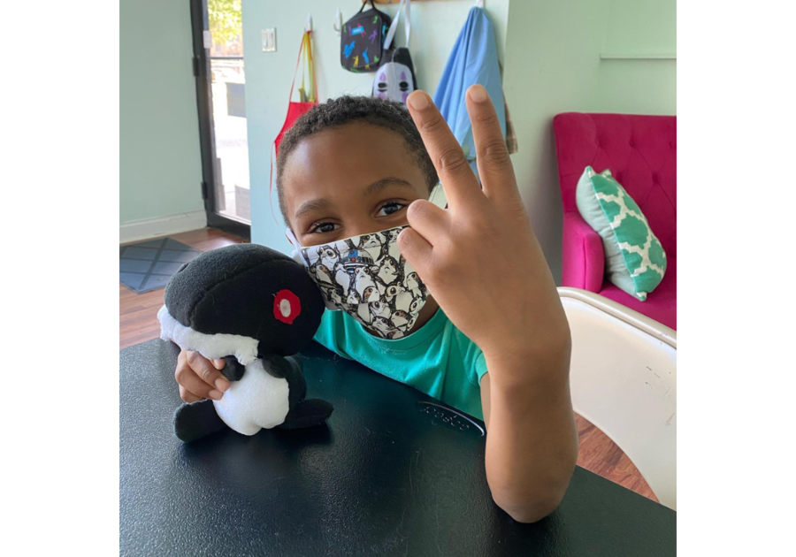 boy wearing mask giving peace sign