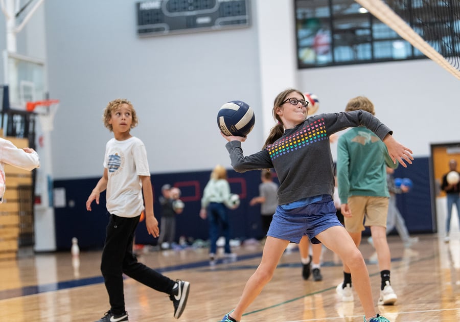 child throwing a ball in the gymnasium at Denver Academy Summer Camp