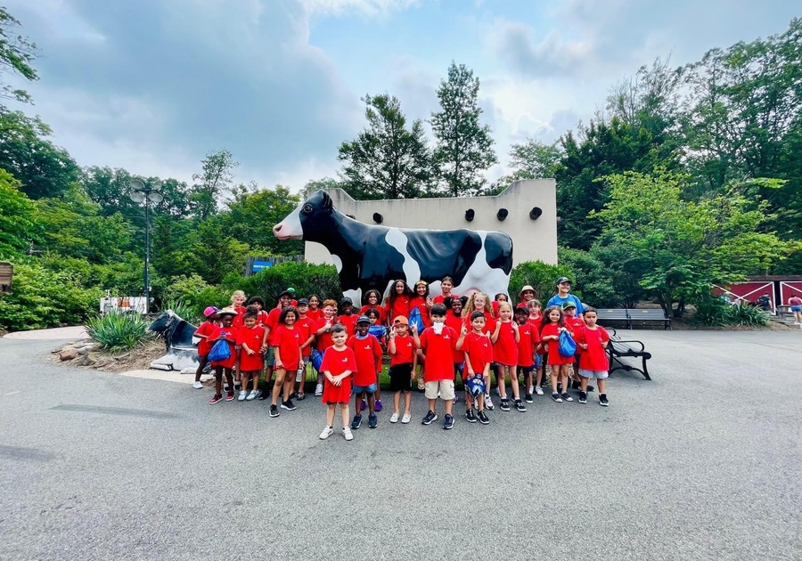 a group of kids in front of giant cow