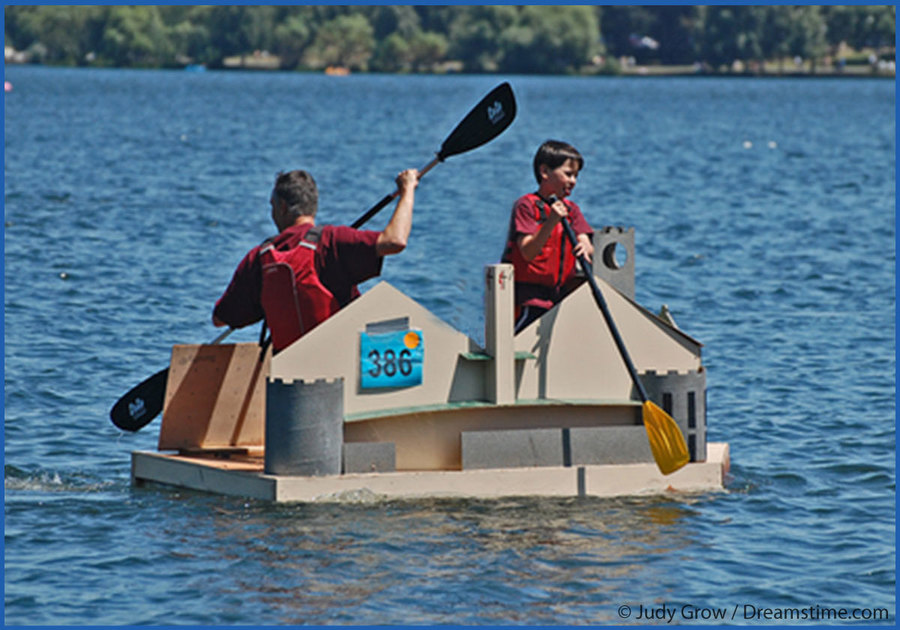 Team paddling cardboard boat in lake