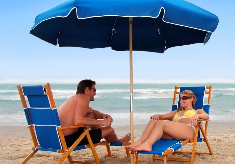couple with beach chairs and blue umbrella