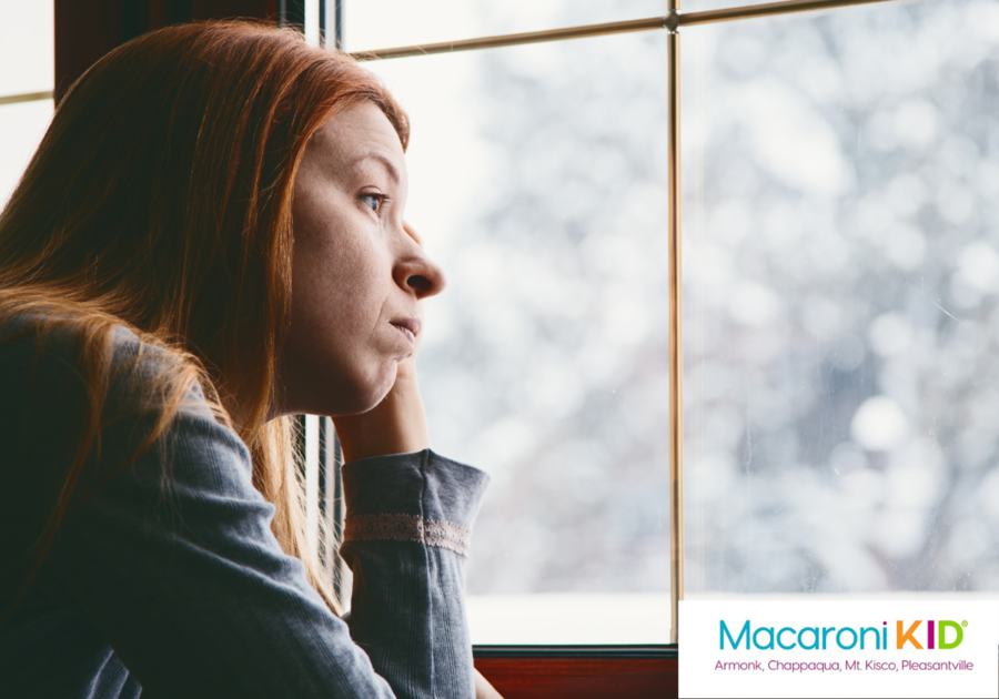 Woman looking out a window at a snowy scene