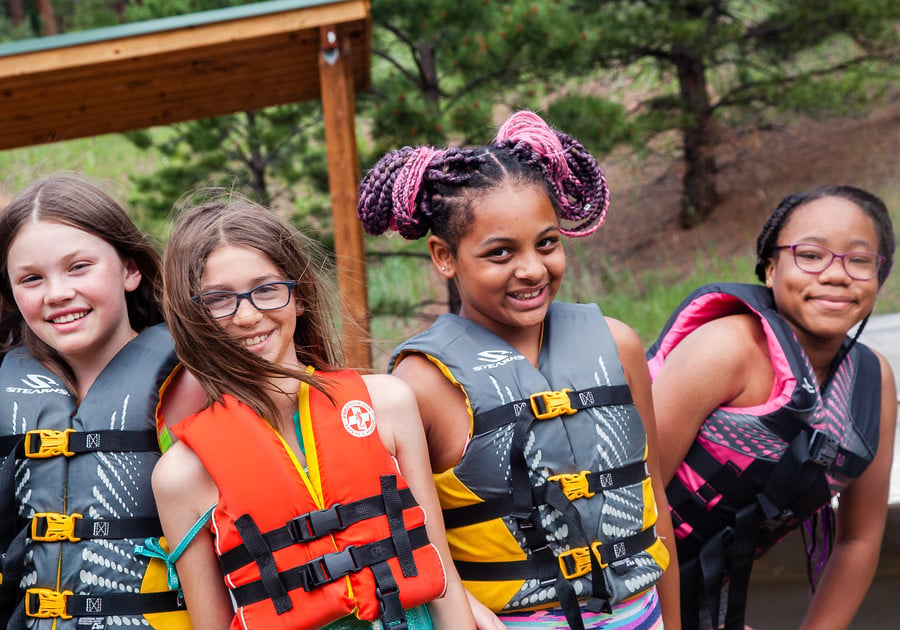 four smiling girls wearing water life vests at Girl Scouts of Colorado summer camp