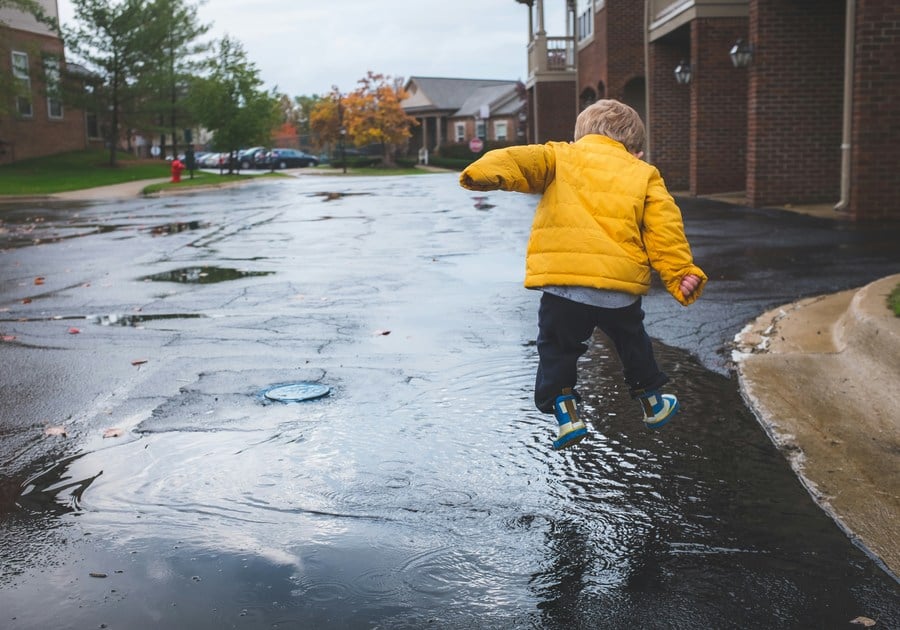 Kid splashing around in puddles during a rainy day