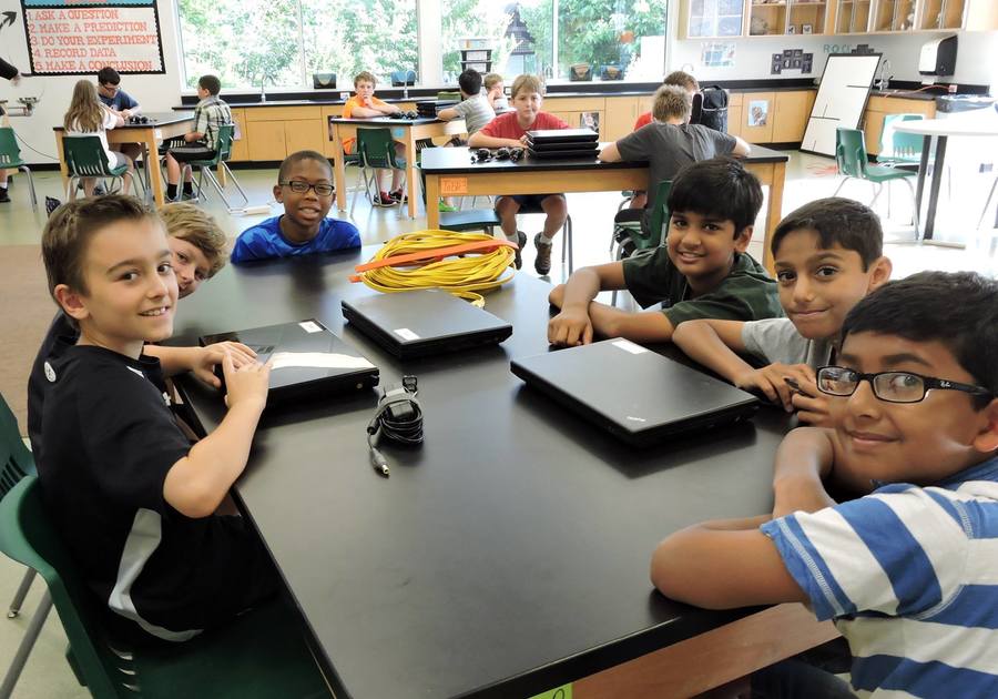 photo of male campers seated at table with computers