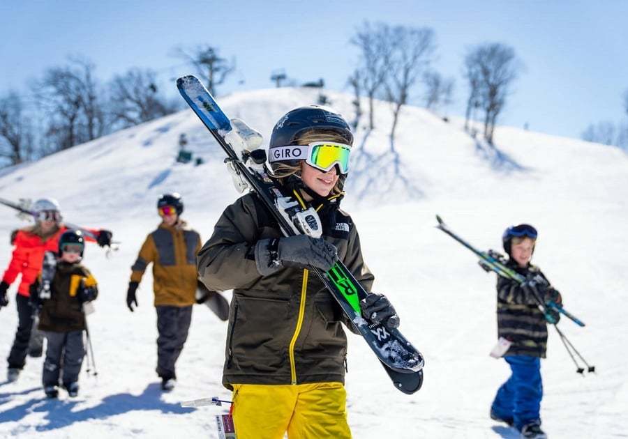 family carrying their skis off the hill