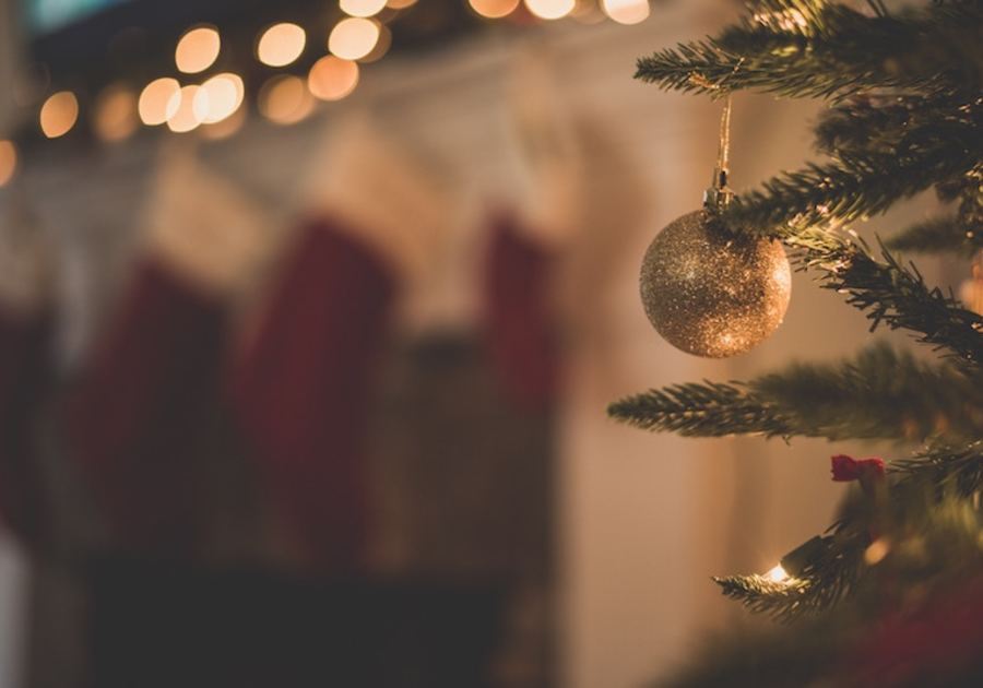 christmas tree and one ornament with stockings on chimney in background