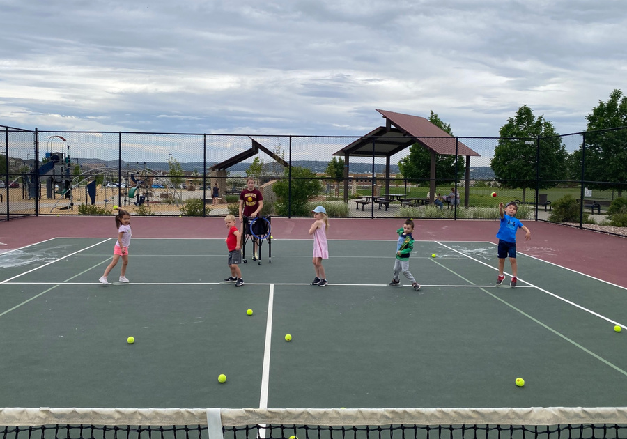 preschoolers throwing tennis balls over the net