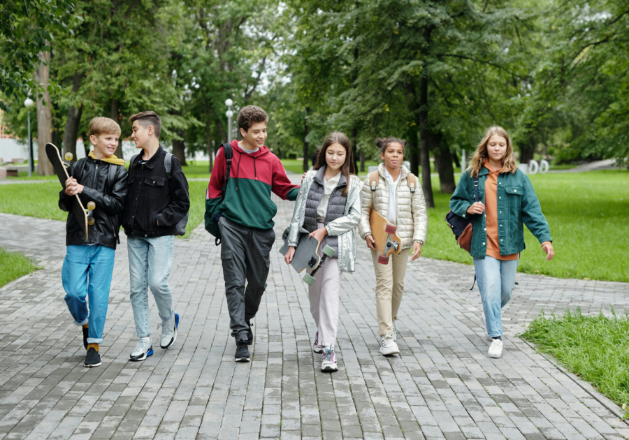 A group of middle school aged kids walking together through a park