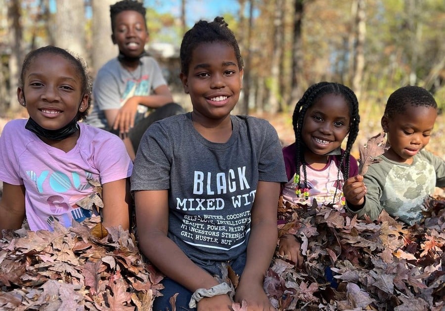 photo of children sitting in leaf pile