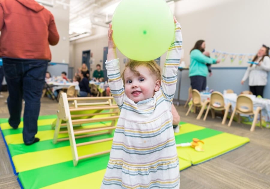 toddler holding a green balloon