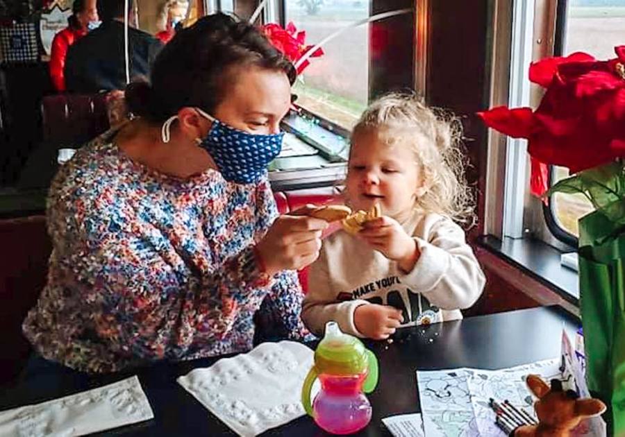 Mom and daughter touching their cookies together while on the dining car of a train