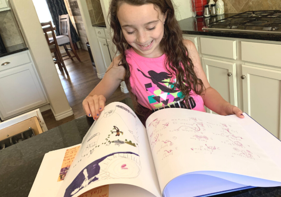 Artimus Art: child looking through her Artimus Art book filled with her personal artwork