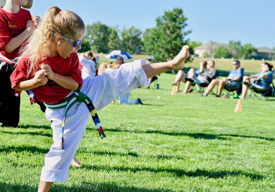 child doing a martial arts kick outside