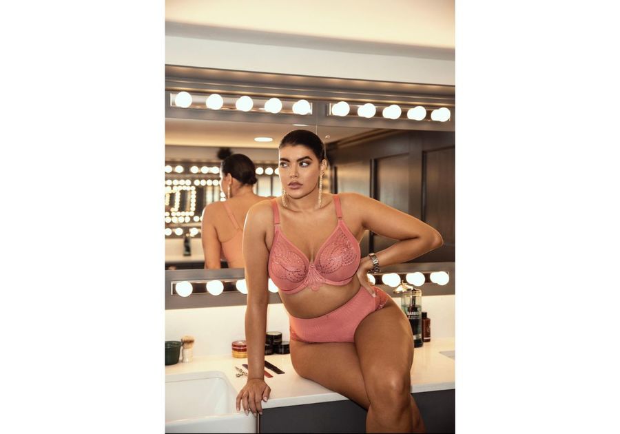 woman in matching pink bra and panties with back to mirror