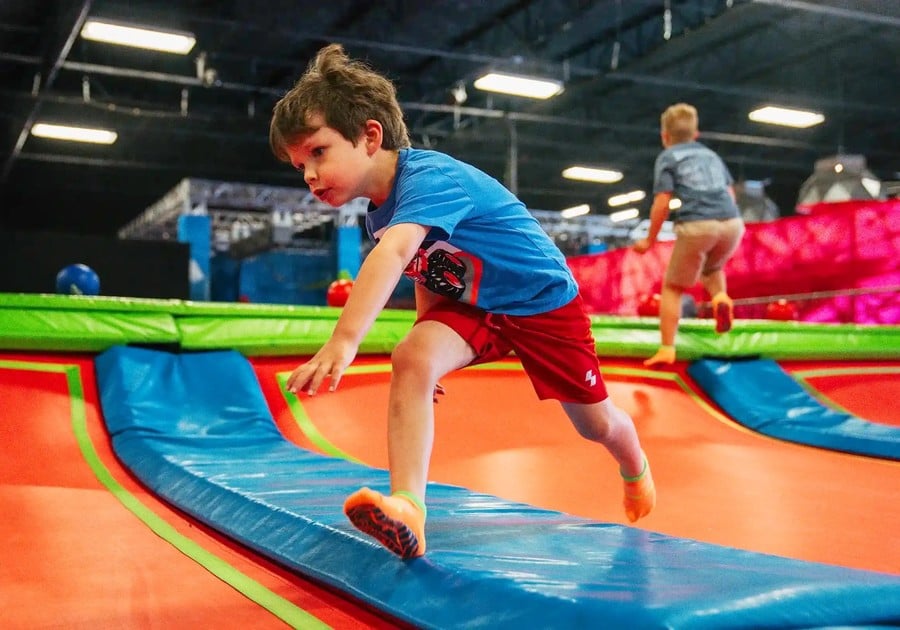 boy leaping over trampolines