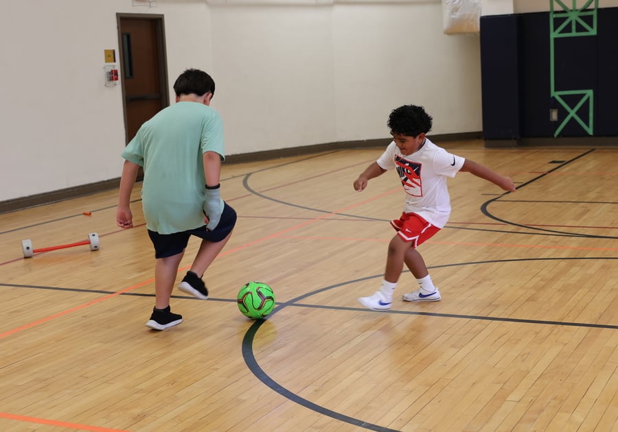 Kids kicking a ball in a gym