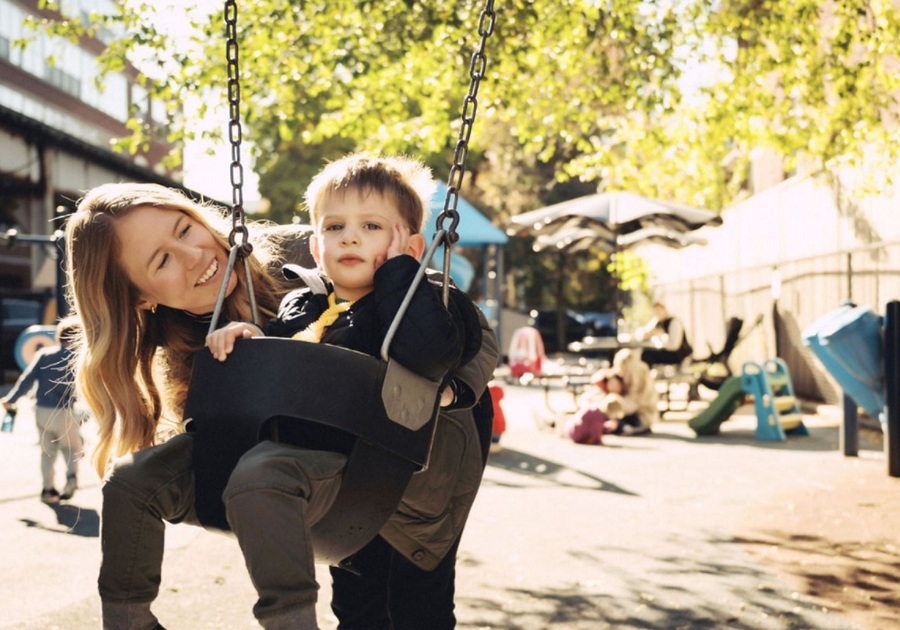 woman pushing toddler on swing