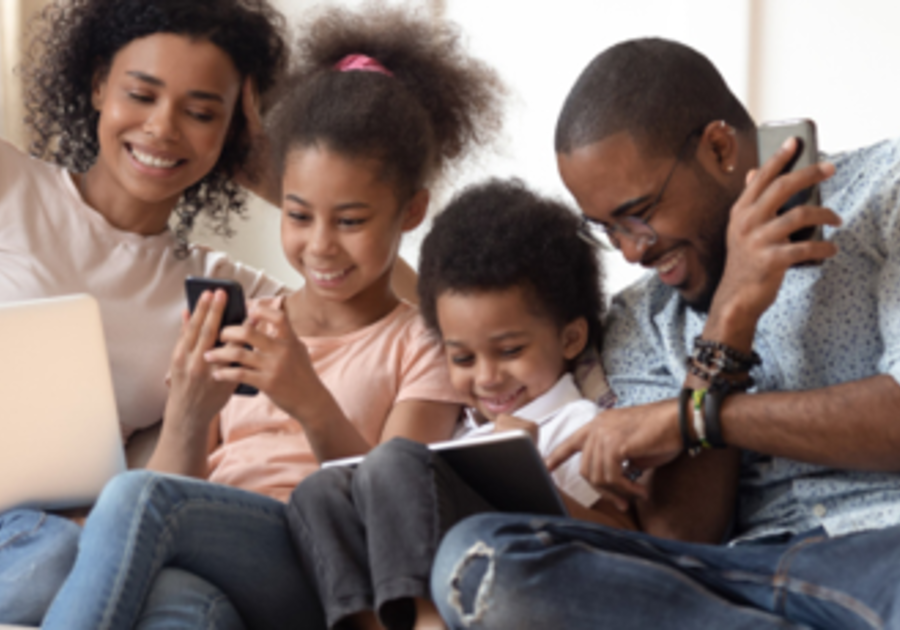 Family looking at electronic devices and smiling