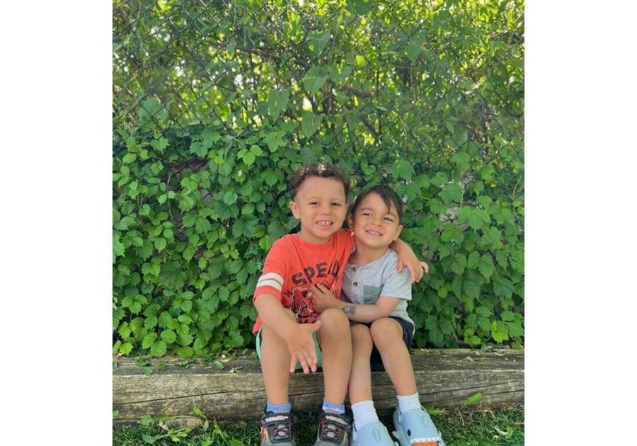 two little boys sitting on a log with their arms around each other