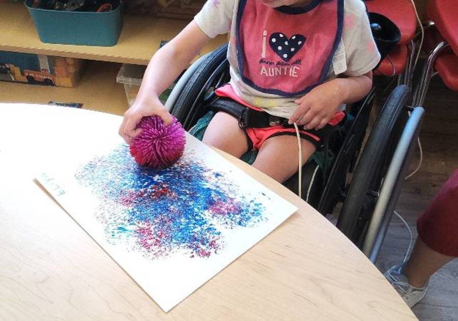 Child painting with a sensory object