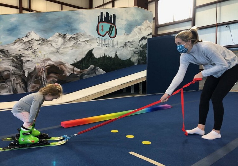 kid being pulled up indoor hill on skis