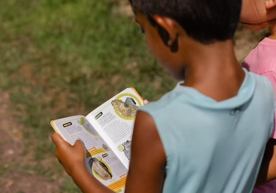 Camp Wonderkin child looking at nature guide