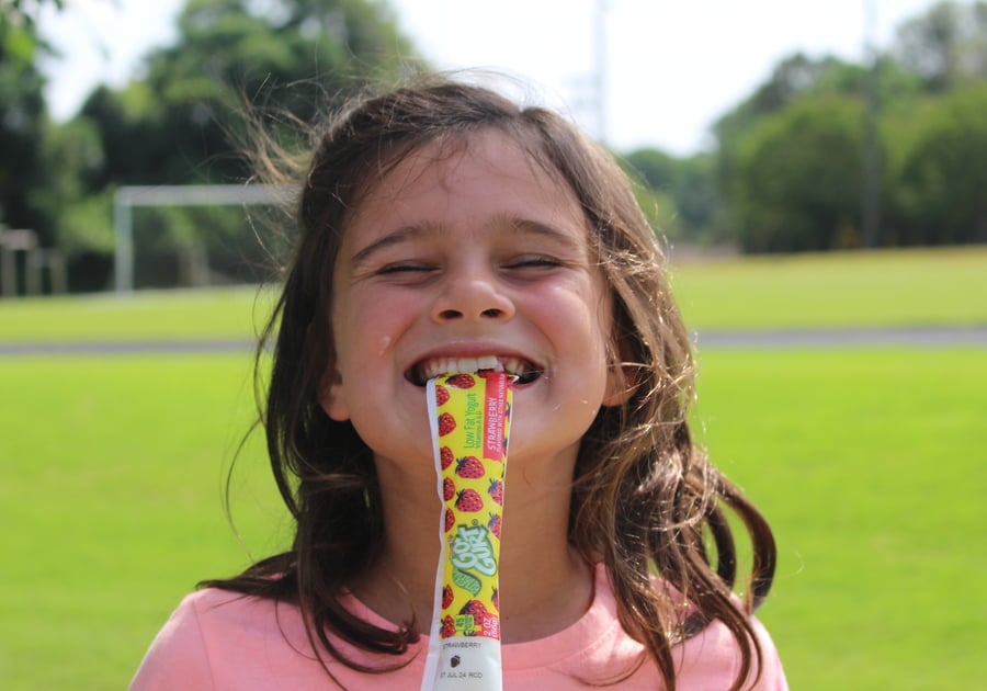 Photo of female camper eating snack outside on field